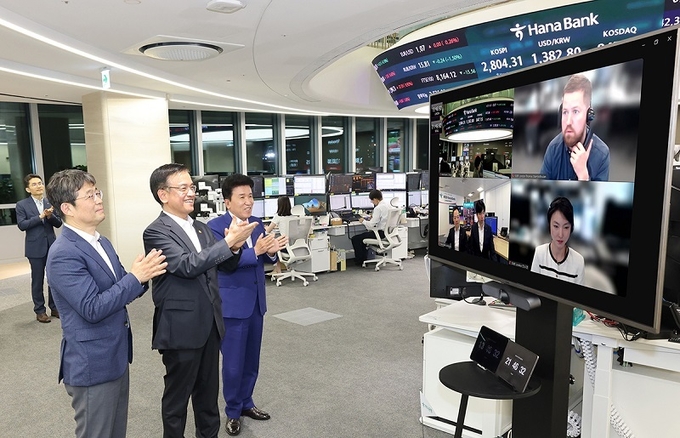 사진설명) 7월 1일 외환시장 개장시간 연장 첫날을 맞아 오후 9시 30분경 최상목 부총리 겸 기획재정부 장관, 유상대 한국은행 부총재가 하나은행 딜링룸을 방문했다. 최상목 부총리(사진 왼쪽 두번째), 유상대 한국은행 부총재(사진 왼쪽 첫번째), 함영주 하나금융그룹 회장(사진 왼쪽 세번째)이 하나은행 런던 지점 및 스테이트스트리트은행(SSBT) 런던 지점과 화상 연결 종료 후 현지 직원들을 격려하고 있다.